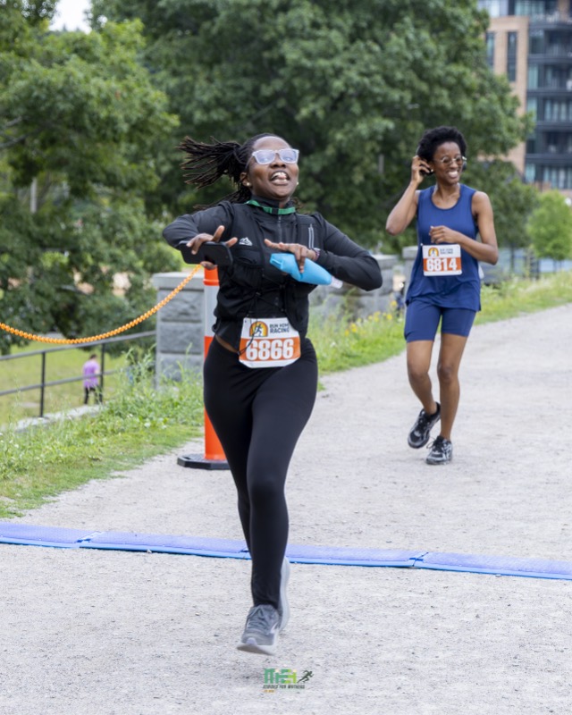 A joyful runner crosses the finish line with arms out