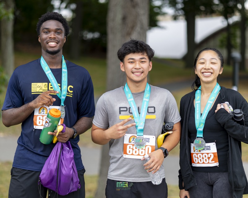 Three smiling finishers show off their Strides for Mothers medals