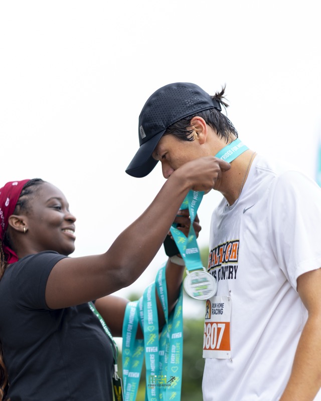 A volunteer places a medal around a finisher's neck