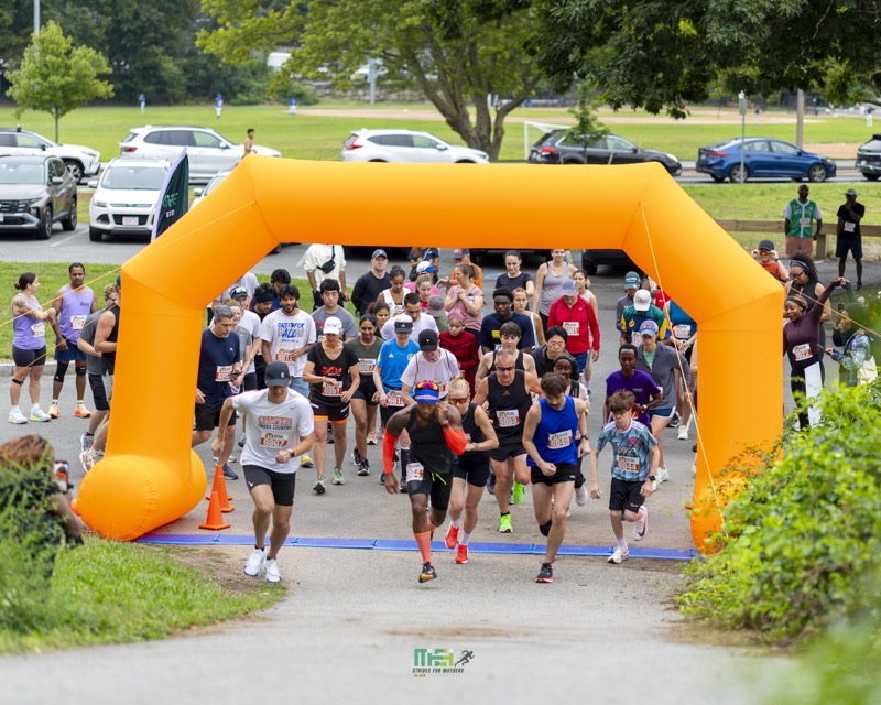 Runners set off under the orange start arch at Chestnut Hill Reservation