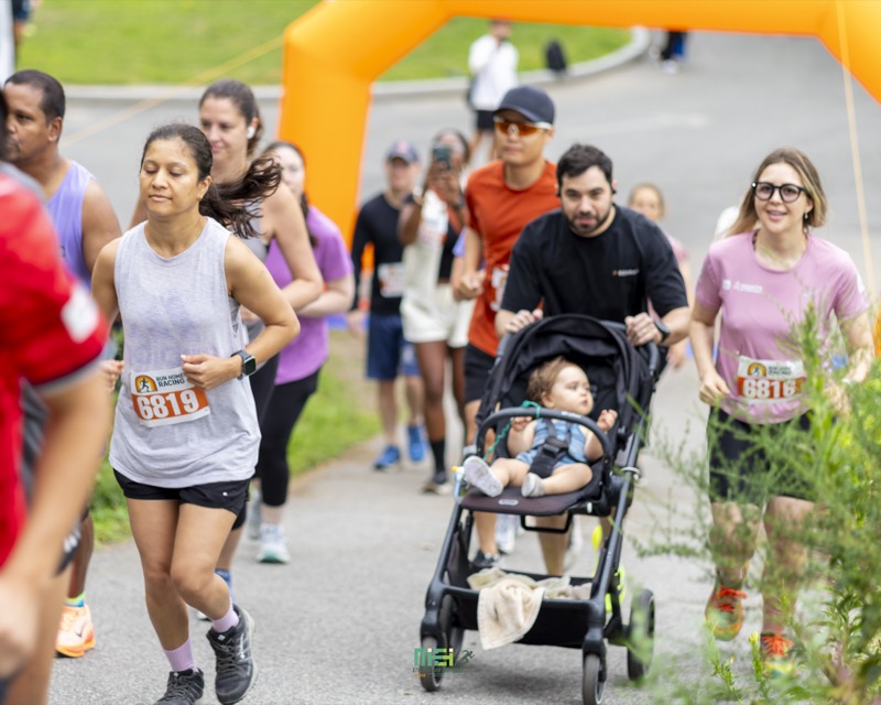 A runner pushes a baby in a stroller alongside other participants